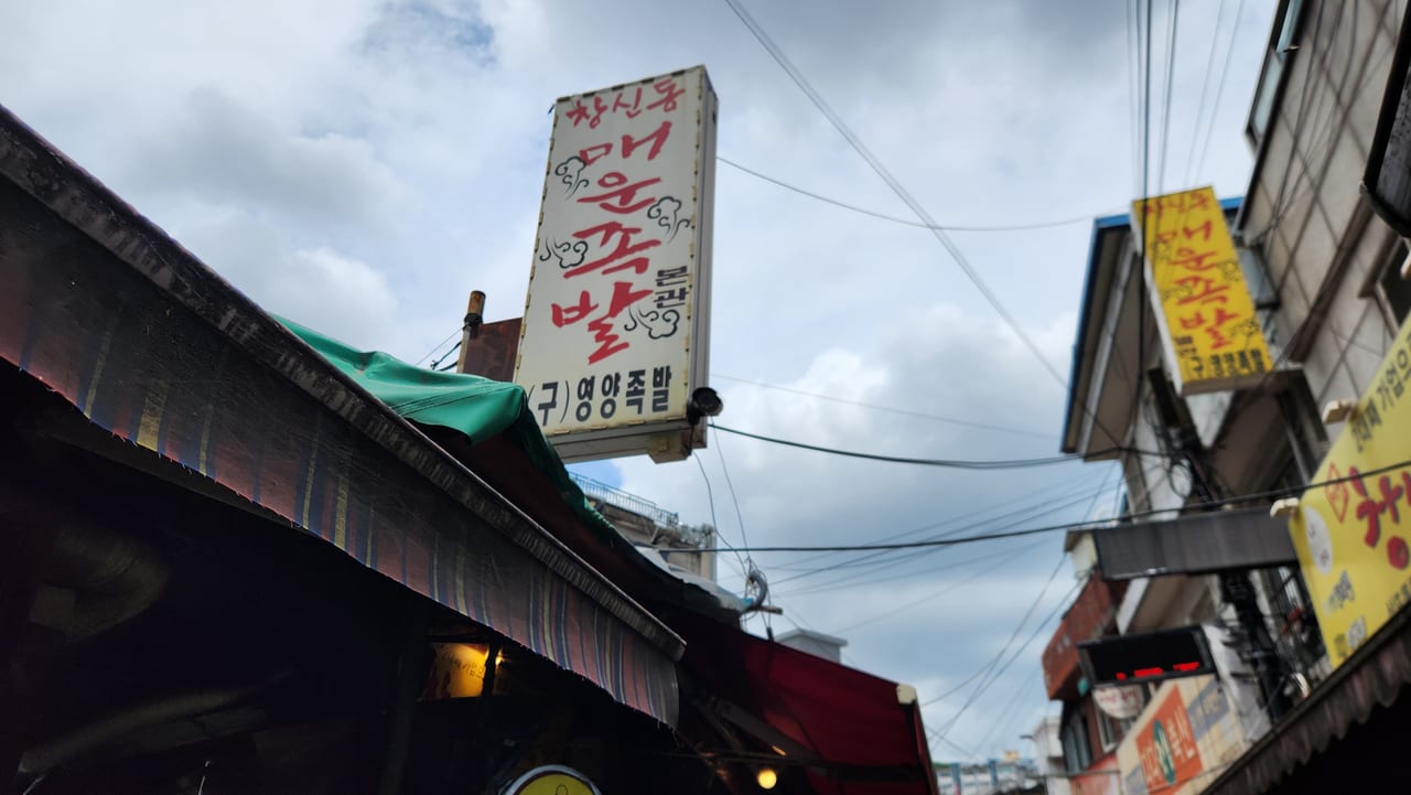 Vertical Korean sign for Changsin-dong Spicy Jokbal above the market alley