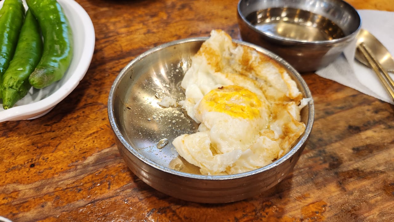 Self-cooked fried egg in a metal dish at Ibukjip Chapssal Sundae