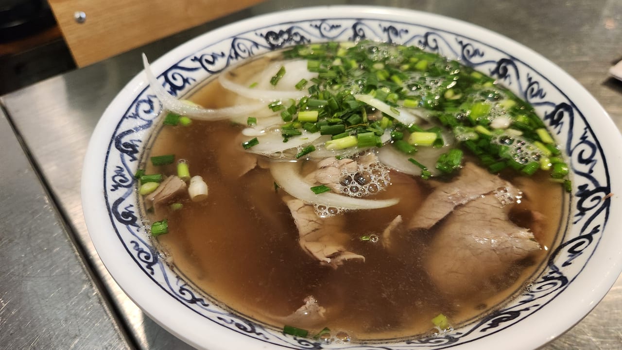 Bowl of Vietnamese beef brisket pho with clear broth and spring onion at Phopular