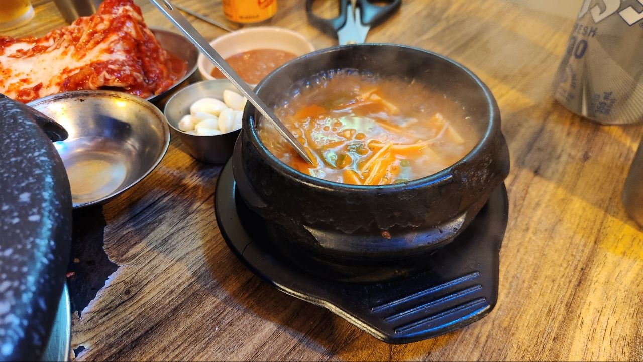 Bubbling Korean soybean paste stew in a black earthenware pot